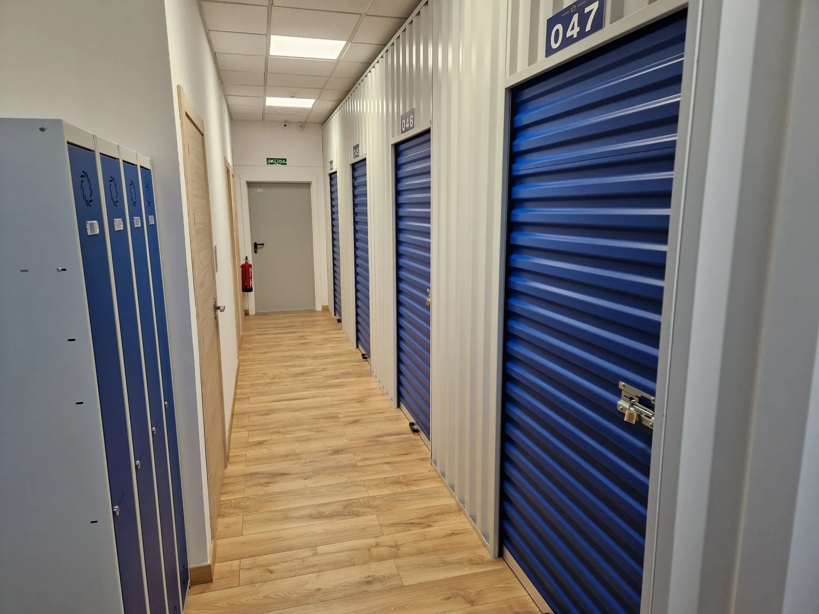 Pasillo de trasteros con persianas azules y suelo de madera